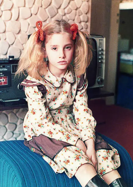 Vintage analog photo of a san/angry girl looking at camera. Vintage image from the seventies of the 20th century.