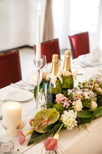 Bottles of champagne, flowers and candles on the wedding table.