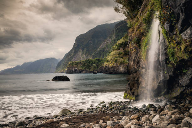 istock Waterfall in a black sand beach with moody cliffs on the background 1401311249