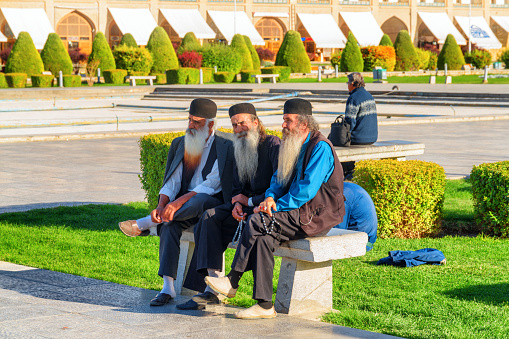 Isfahan, Iran - 23 October, 2018: Elderly Iranian men resting in Naqsh-e Jahan Square. The square is a popular tourist destination of the Middle East and recreational gathering place among residents.