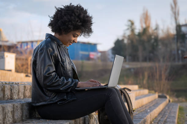 istock Happy young woman sitting on stairs using laptop 1401312407