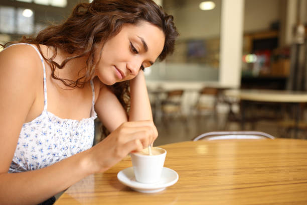 istock Pensive woman stirring coffee sitting in a restaurant 1401312507