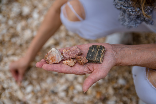 Adult Woman Picking Up Interesting and Beautiful Small Stones in Hand from the Ground of Vacation location for Souvenir