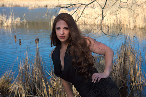 beautiful woman outdoor portrait elegance black dress long hair brunette in front of water pond