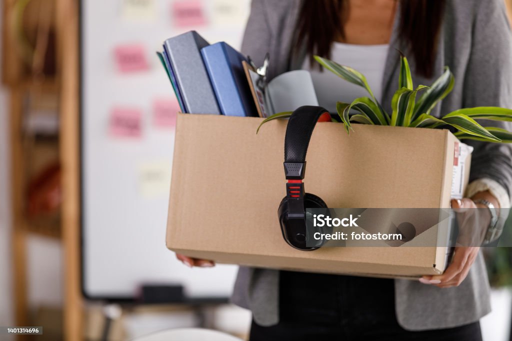Businesswoman holding a cardboard box with personal belongings Midsection of unrecognizable businesswoman holding a cardboard box with personal belongings, either hired of fired. Belongings Stock Photo