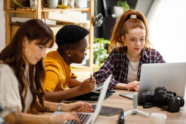 istock Three diverse female entrepreneurs sitting at table in a creative studio, co-working 1401315232
