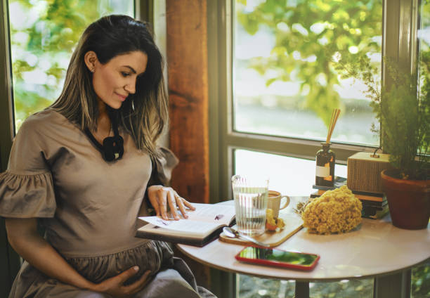 piękna kobieta w ciąży czytająca książkę w kawiarni. - book reading dress women zdjęcia i obrazy z banku zdjęć