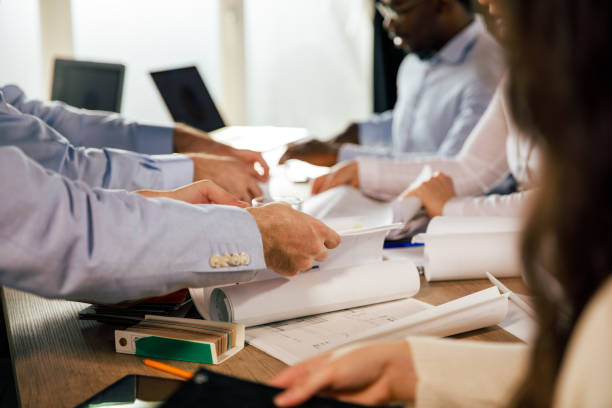 istock Businessmen rolling out plans and technical drawings during a project meeting 1401316504