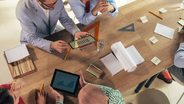 istock Business people having a meeting at conference table, reviewing graphs on digital tablets 1401317787