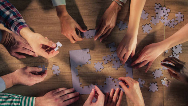 istock Close up shot of hands solving jigsaw puzzle on a wooden table 1401318320