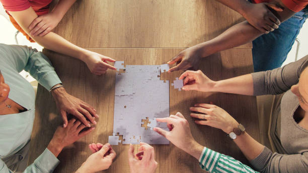istock Copy space shot of people adding last  pieces to the jigsaw puzzle they are almost done solving 1401318321