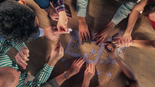 istock Group of diverse friends working as a team, solving a jigsaw puzzle 1401318324