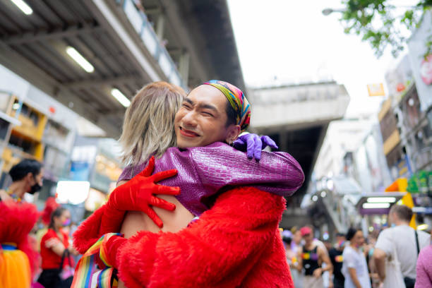 glückliches asiatisches paar, das spaß an der lgbtq-pride-parade auf der straße hat. - homosexual gay man parade flag stock-fotos und bilder