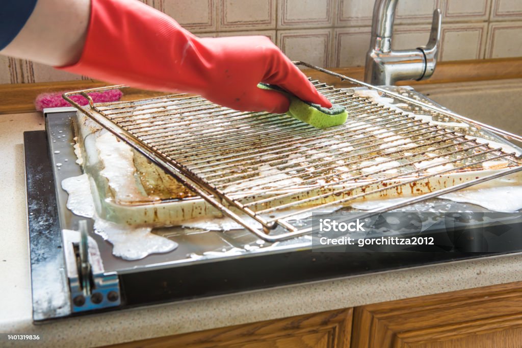 Cleaning the oven. man's hand in household cleaning gloves cleans oven inside. Oven Stock Photo