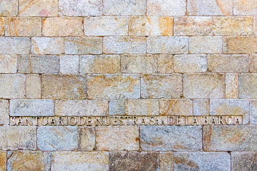 Virxe da Barca Sanctuary church,  carved information sign on stone side wall. Muxía, Costa da Morte, Galicia, Spain