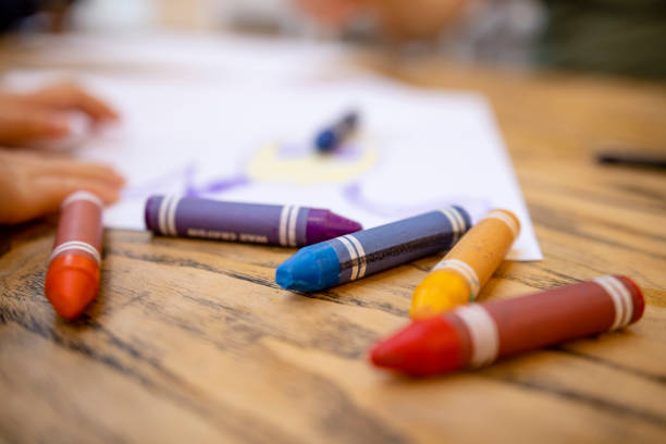Colourful Crayons on Table A close-up shot of colourful crayons on a wooden table with paper. child care stock pictures, royalty-free photos & images