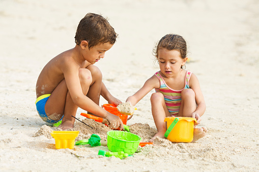 Two children playing in the sand on their summer vacation