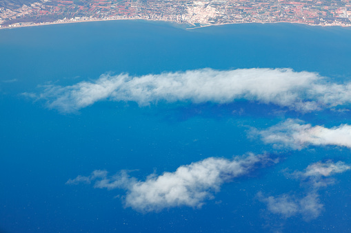 Flight over the ocean and continent . Aerial view of clouds and coast