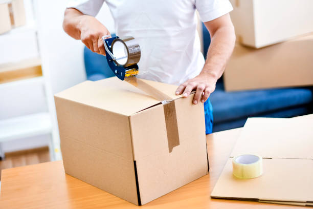 istock Worker hands holding packing machine and sealing cardboard or paper boxes 1401325682