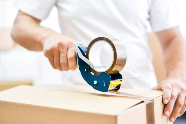 istock Worker hands holding packing machine and sealing cardboard or paper boxes 1401325685