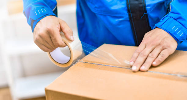 istock Worker hands holding packing machine and sealing cardboard or paper boxes 1401325704