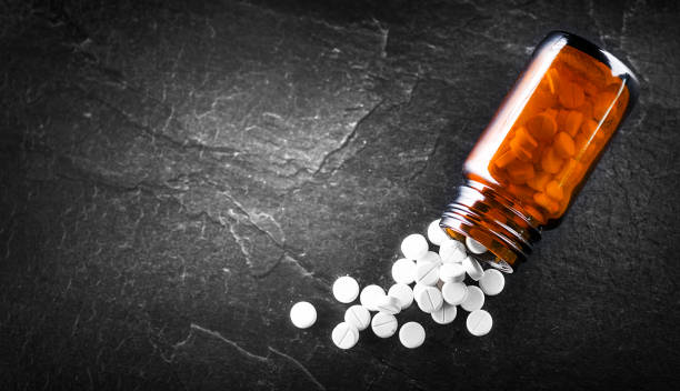 istock White medical pills or tablets with bottle on black background. Macro side view with copy space 1401325738