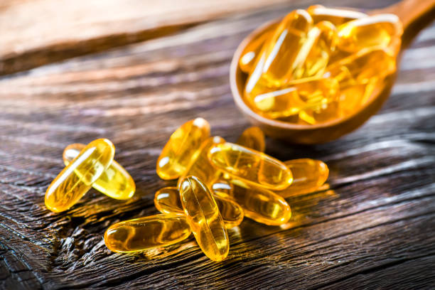 istock Omega 3 capsules oil on wooden background in rustic spoon. 1401325762