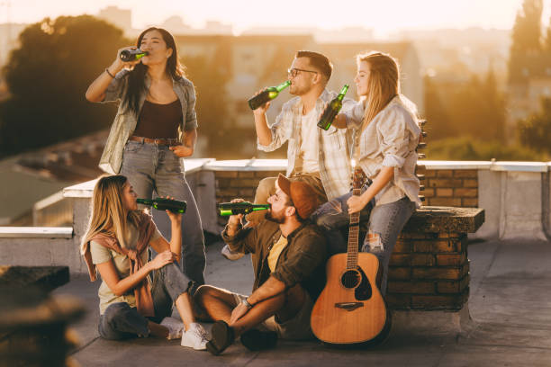 istock Young friends drinking beer on a rooftop at sunset. 1401327092