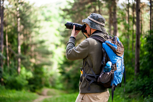 Image of man photographing  while hiking in the nature.