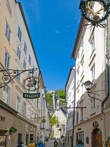 Getreidegasse, Salzburg, Austria, with shop signs hung over the narrow street and tourists walking along it.