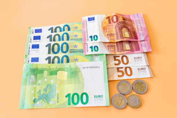 istock Various euro banknotes and coins on orange background 1401327484