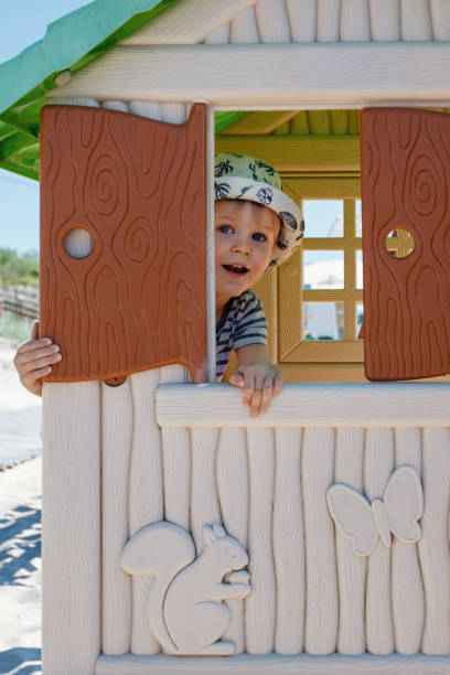 istock A cute boy is hiding in a small toy house, he is watching through an open shutter. 1401328227