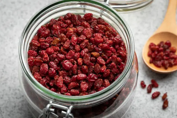 Glass jar with dried red Iranian barberries close up