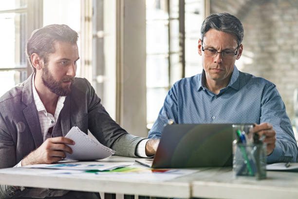istock Businessmen brainstorming while working on paperwork and a computer in the office. 1401328681
