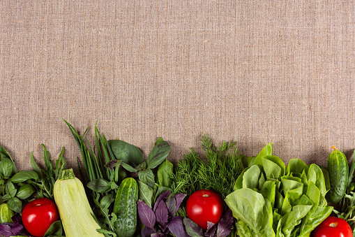 Fresh vegetables and herbs on linen cloth background with copy space on the top. Healthy food concept.