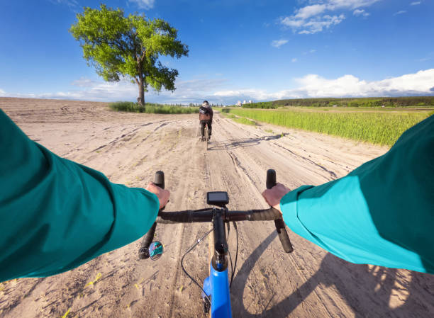 ciclista su bici gravel pedala lungo la strada di sabbia nel campo. pov. - bikers point of view foto e immagini stock