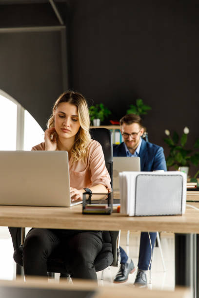 istock Business people sitting in a row, at their desks, using laptops, working diligently 1401331708