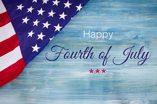 Happy 4th of July written on a blue rustic wood background with an American flag.