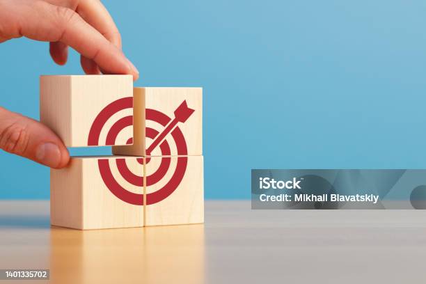 Male Hand Putting Stack Of Wooden Blocks With Target Icon On Wooden Table Blue Background Copy Space Stock Photo - Download Image Now