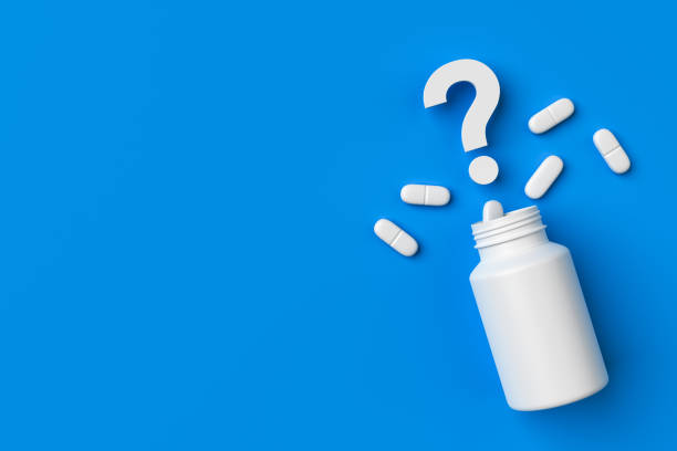 istock Plastic medical container and white capsule pills with question mark on blue background copy space top view. 1401335738