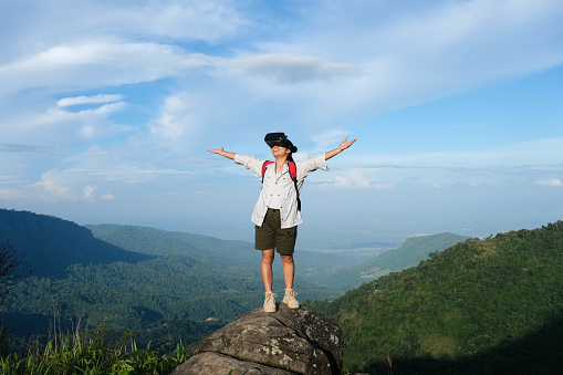 Happy adventure woman wearing vr headset augmented reality virtual reality in beautiful mountain landscape concept. Young woman using virtual reality glasses stands on a cliff on top of a mountain.