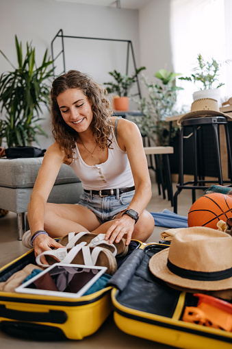 Young woman preparing for road trip, packing suitcase