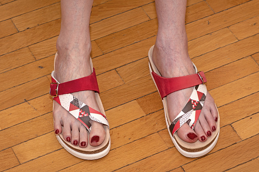 Female feet in open toe sandals with painted red nails pedicure