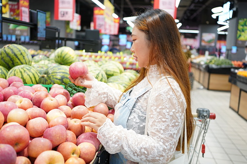 A young woman selects fruit in a supermarket