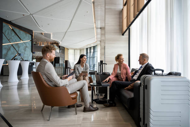 Four colleagues sitting in a luxury hotel lobby and preparing for a business meeting. stock photo