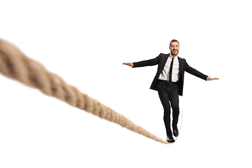 Businessman walking on a tightrope and smiling isolated on white background