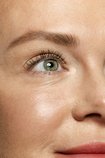 Close-up portrait of young woman's eyes with first wrinkles. Female model with well-kept skin. Concept of women's health and beauty, cosmetology, cosmetics, self-care, skin care. Anti-aging.