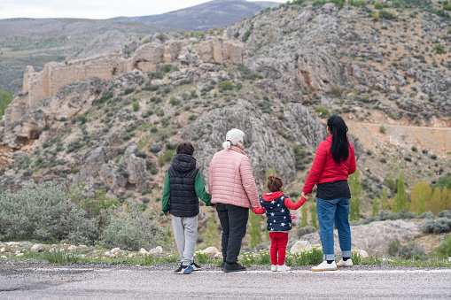 Photo of senior woman, mature daughter, grandson and granddaughter looking at old ruin of castle. Shot in outdoor with a full frame mirrorless camera