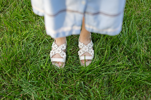 Girlâs feet in mint green sandals shoes standing outdoor on the pavement. Fashion - spring or summer footwear for woman - close up.