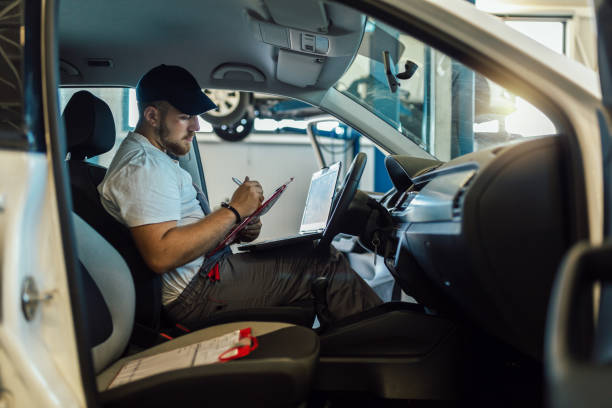 istock Professional car mechanic working in auto repair service using laptop. 1401346993